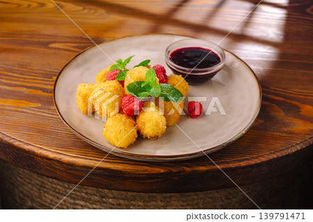 Fried dough balls served with raspberry sauce on a wooden table Fried dough balls served with raspberry sauce on a wooden table 139791471