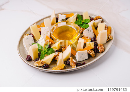 Cheese and nut platter with honey served on a round plate for snack time 139791483