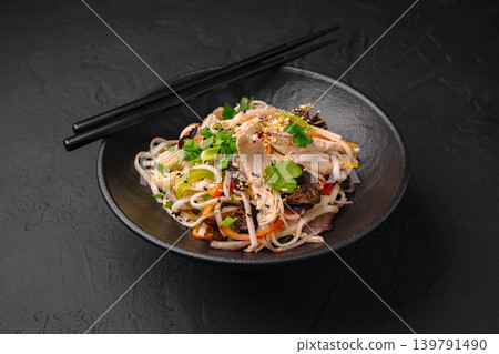 Noodles with chicken, vegetables, and herbs served in a black bowl 139791490