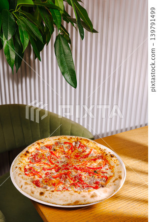 Freshly made pizza on a wooden table with green plants nearby Freshly made pizza on a wooden table with green plants nearby 139791499
