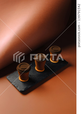 Miniature chocolate cups arranged on a slate board with a brown backdrop Miniature chocolate cups arranged on a slate board with a brown backdrop 139791542