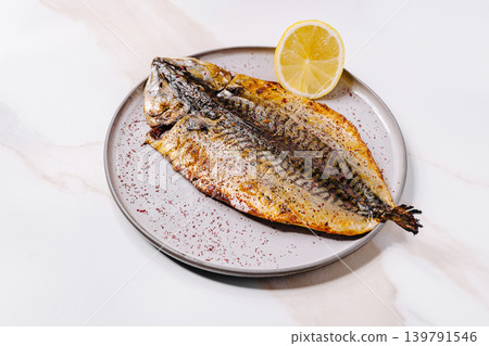 Grilled fish served on a plate with a slice of lemon and seasoning Grilled fish served on a plate with a slice of lemon and seasoning 139791546