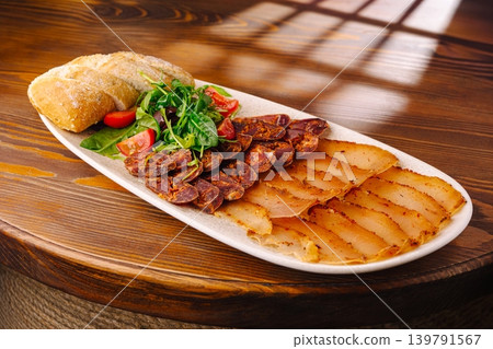 Delicious platter of cured meats, bread, and salad served at a dining table Delicious platter of cured meats, bread, and salad served at a dining table 139791567