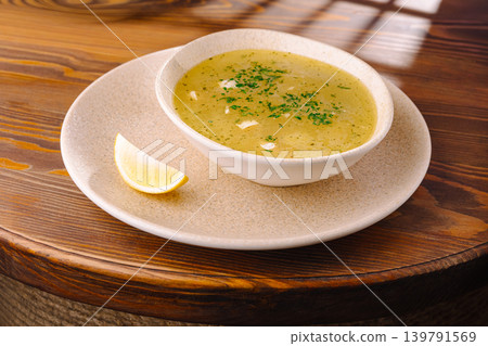 Warm bowl of soup with lemon slice on wooden table during daytime Warm bowl of soup with lemon slice on wooden table during daytime 139791569