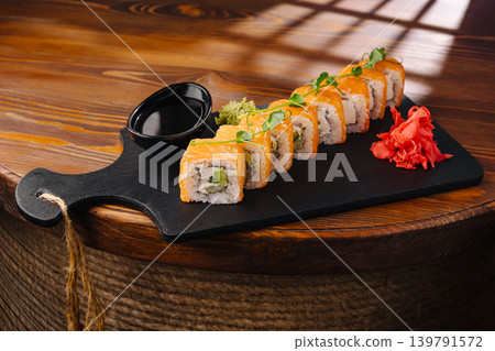 Sushi rolls served on a black board with dipping sauce and garnishes Sushi rolls served on a black board with dipping sauce and garnishes 139791572