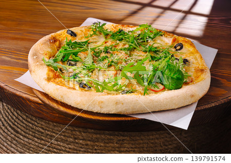 Fresh pizza sits on a wooden table in a cozy setting with sunlight shining Fresh pizza sits on a wooden table in a cozy setting with sunlight shining 139791574
