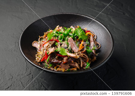 Bowl of noodles with meat and vegetables on dark surface 139791606