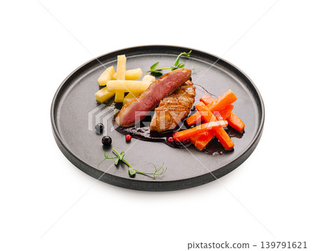 Gourmet duck dish served on a dark plate with colorful vegetables and sauce Gourmet duck dish served on a dark plate with colorful vegetables and sauce 139791621