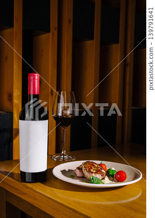 Dinner setting with wine and plated food on a wooden table 139791641