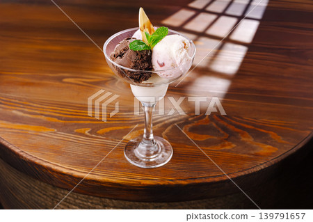 Chocolate and strawberry ice cream served in a glass on a wooden table 139791657