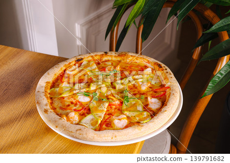 Fresh pizza on wooden table with green plant in background 139791682