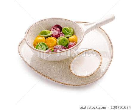 Colorful ravioli or dumplings and sauce served in a bowl on a plate Colorful ravioli or dumplings and sauce served in a bowl on a plate 139791684