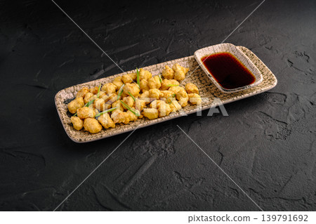 Crispy fried food served on a plate with dipping sauce on dark surface Crispy fried food served on a plate with dipping sauce on dark surface 139791692