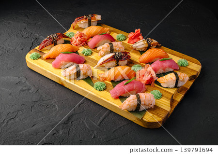 Different types of sushi served on wooden board with garnishes and sauces Different types of sushi served on wooden board with garnishes and sauces 139791694