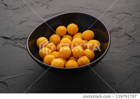 Snack balls in a black bowl on a textured surface at a kitchen table Snack balls in a black bowl on a textured surface at a kitchen table 139791707