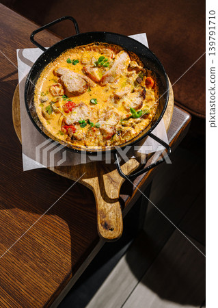 A skillet filled with a tasty meal is set on a wooden serving board A skillet filled with a tasty meal is set on a wooden serving board 139791710