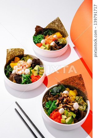 Bowls of sushi and salad on a white table with orange backdrop Bowls of sushi and salad on a white table with orange backdrop 139791717