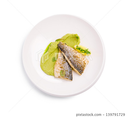 Fresh fish served with green puree and lemon butter on a white plate Fresh fish served with green puree and lemon butter on a white plate 139791729