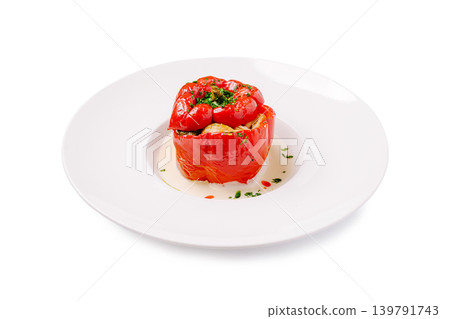 Stuffed red pepper with herbs served on a white plate in a kitchen setting 139791743
