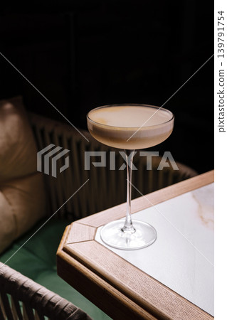 Cocktail served on a wooden table in a cozy bar space during the evening Cocktail served on a wooden table in a cozy bar space during the evening 139791754