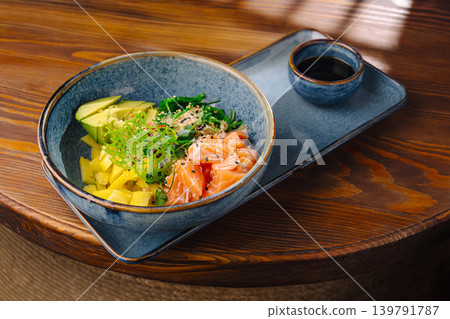 Fresh sushi bowl with salmon, avocado, and soy sauce on wooden table Fresh sushi bowl with salmon, avocado, and soy sauce on wooden table 139791787