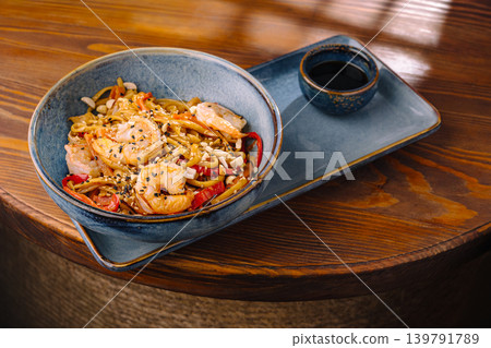 Shrimp stir fry with vegetables served in bowl on wooden table Shrimp stir fry with vegetables served in bowl on wooden table 139791789