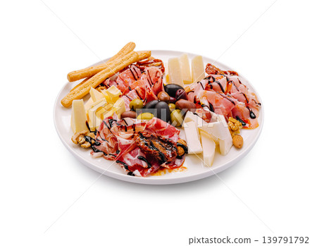 Assorted meats, cheeses, breadsticks, and olives on a white plate Assorted meats, cheeses, breadsticks, and olives on a white plate 139791792