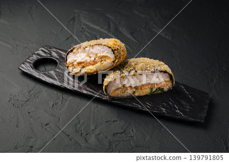 This sushi burger features fried salmon filled with seafood, cut in half to show the filling. This sushi burger features fried salmon filled with seafood, cut in half to show the filling. 139791805
