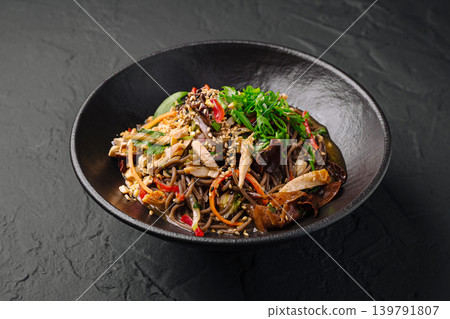 Warm soba noodle dish with vegetables and chicken served in a black bowl 139791807