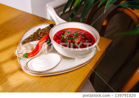 Delicious borsch soup served with bread and cream in a cozy setting during lunch Delicious borsch soup served with bread and cream in a cozy setting during lunch 139791820
