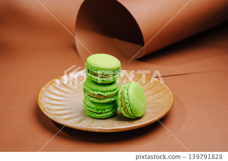 Green macarons are stacked on a brown plate Green macarons are stacked on a brown plate 139791828