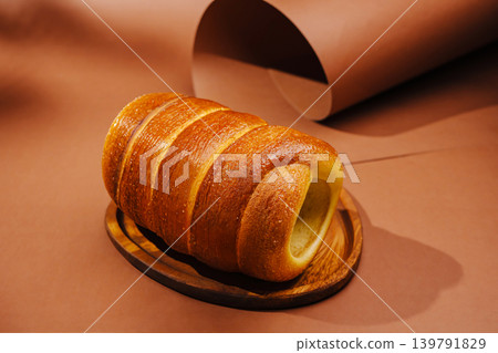 Freshly baked bun displayed on a wooden plate on a brown surface 139791829