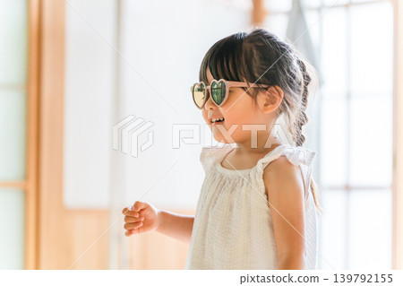 A girl wearing sunglasses plays pretend as a model in a fashion show. A girl wearing sunglasses plays pretend as a model in a fashion show. 139792155