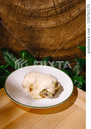 Delicious dish served on a white plate with wood background and green leaves Delicious dish served on a white plate with wood background and green leaves 139792270