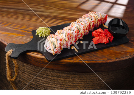 Sushi roll served on a wooden platter with wasabi and ginger on the side Sushi roll served on a wooden platter with wasabi and ginger on the side 139792289
