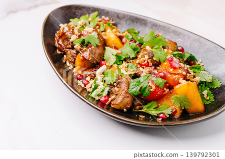 Savory dish with meats, fruits, and herbs served on a dark plate Savory dish with meats, fruits, and herbs served on a dark plate 139792301