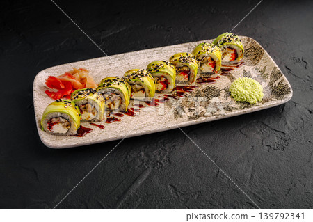Green dragon sushi rolls with avocado and eel served with wasabi and ginger on a decorative plate Green dragon sushi rolls with avocado and eel served with wasabi and ginger on a decorative plate 139792341