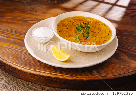 Warm soup served with lemon and yogurt on a wooden table in a restaurant 139792380