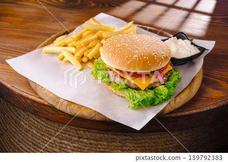 Freshly made burger and fries served on a wooden plate at a restaurant Freshly made burger and fries served on a wooden plate at a restaurant 139792383