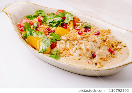 Fresh salad with fruits, nuts, and herbs served on a white plate Fresh salad with fruits, nuts, and herbs served on a white plate 139792393