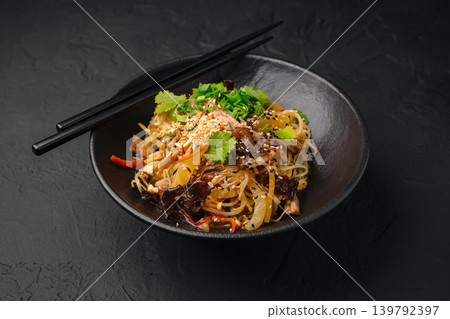Tasty dish of noodles with vegetables and herbs served in a black bowl Tasty dish of noodles with vegetables and herbs served in a black bowl 139792397