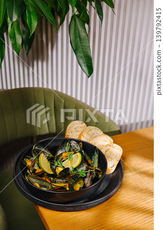 Delicious mussels with lime and bread served on a wooden table 139792415