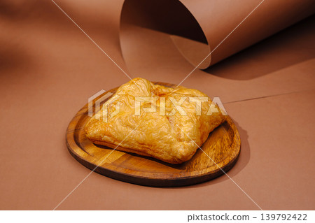 Golden pastry on a wooden plate with brown background Golden pastry on a wooden plate with brown background 139792422
