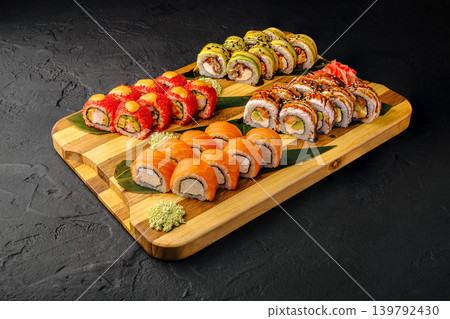 Variety of sushi rolls arranged on a wooden board in a restaurant setting Variety of sushi rolls arranged on a wooden board in a restaurant setting 139792430