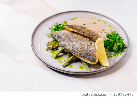 Fresh fish dish with green beans and lemon on a plate Fresh fish dish with green beans and lemon on a plate 139792473