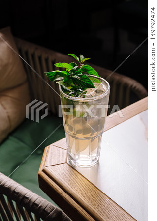 Mint drink served in a tall glass on a wooden table in a dim setting Mint drink served in a tall glass on a wooden table in a dim setting 139792474