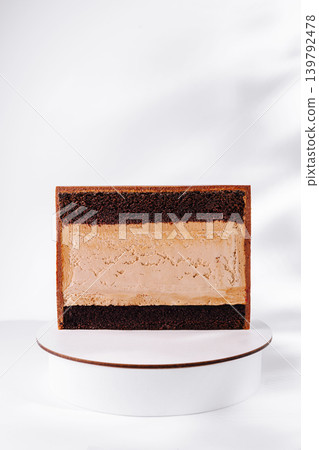 Delicious layered cake displayed on a white pedestal with a simple backdrop 139792478