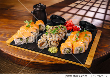 Sushi platter arranged on a wooden table with garnish and sauces Sushi platter arranged on a wooden table with garnish and sauces 139792497