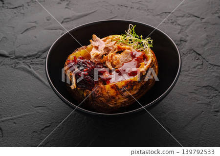 Baked potato with meat and sauce served in black bowl Baked potato with meat and sauce served in black bowl 139792533