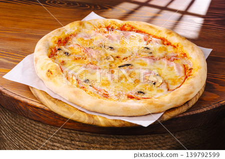 Freshly baked pizza with cheese and toppings on wooden table in restaurant Freshly baked pizza with cheese and toppings on wooden table in restaurant 139792599